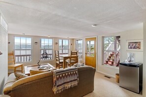 A cozy living room with a sofa, a coffee machine, and a dining area with chairs and a table. - Lakeview Manor With Historic Charm and Serene Waters (Osage Beach)