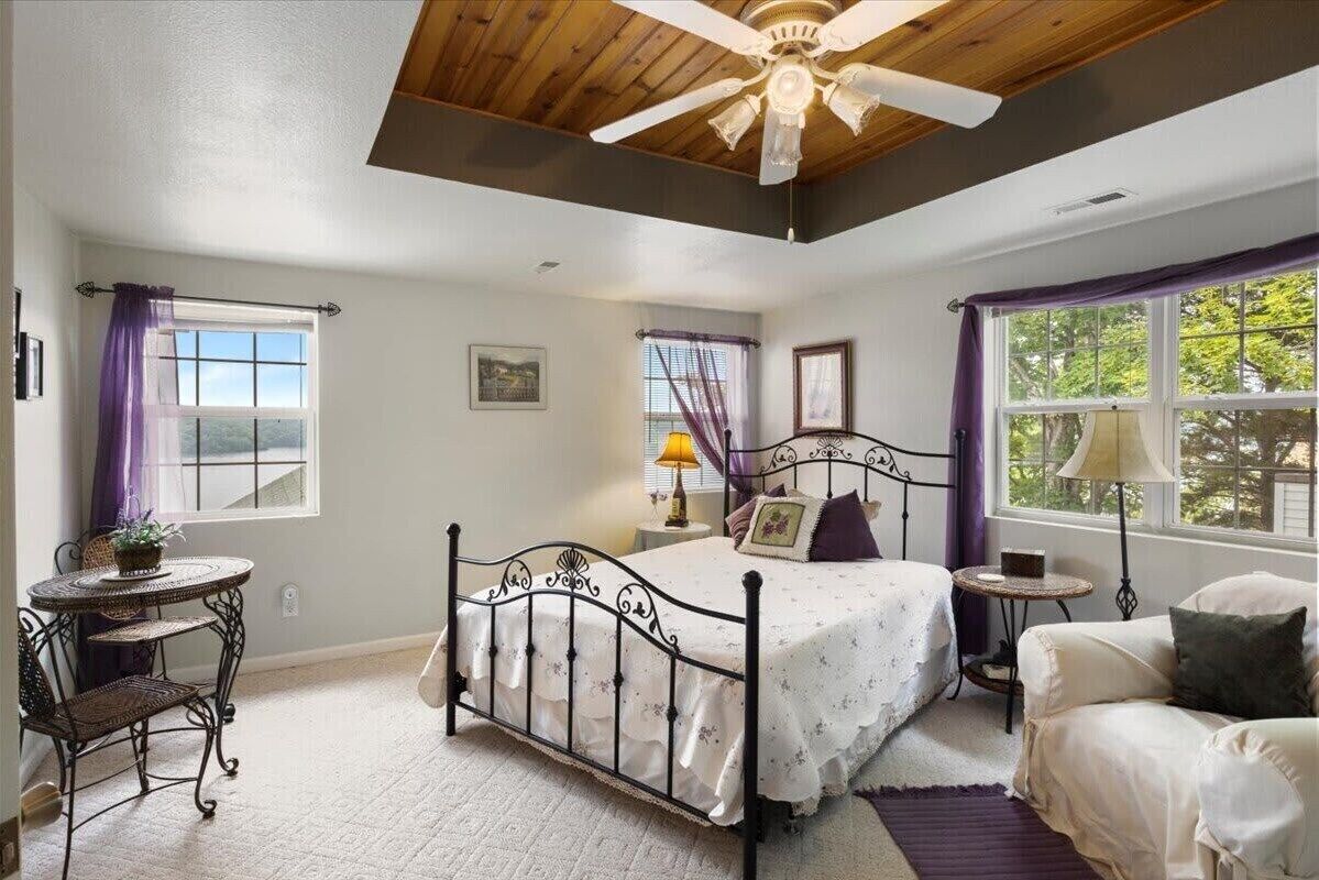 Un dormitorio con cama, escritorio, silla y ventana con cortinas.