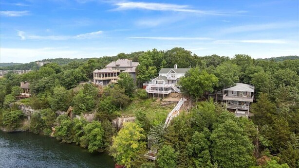 A coastal property with multiple houses, a dock, and a bridge. - Lakeview Manor With Historic Charm and Serene Waters (Osage Beach)