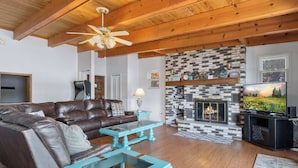 Una sala de estar con chimenea, sofá de cuero y televisor.