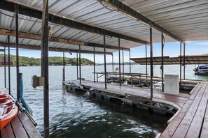 A covered dock area with wooden benches and a boat launch ramp. - Lakefront Home With Huge Views and Great Fishing (Eldon)