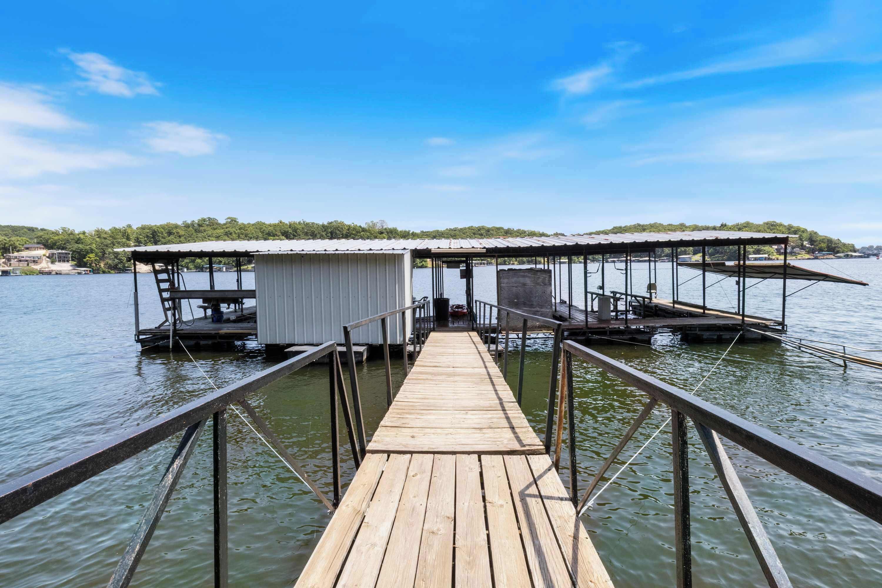 A wooden dock leading to a floating structure with a covered area and a small boat docked nearby.