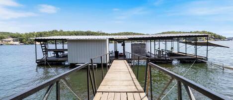 A wooden dock leading to a floating structure with a covered area and a small boat docked nearby.