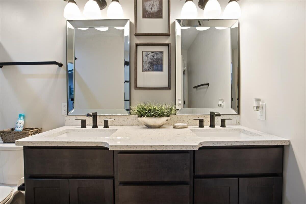 A bathroom with a double vanity, two sinks, a large mirror, and overhead lighting.