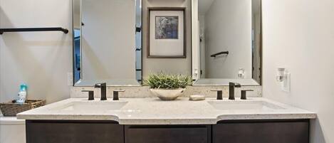 A bathroom with a double vanity, two sinks, a large mirror, and overhead lighting.