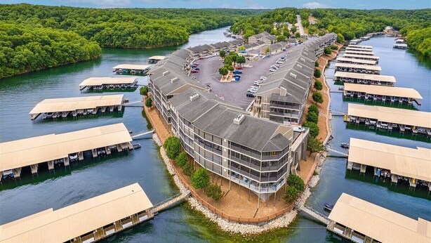 A riverside hotel with multiple floating pontoons, a parking area, and a central building with a curved roof. - Lakefront Condo Near the State Park (Osage Beach)