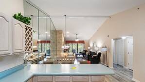 A spacious kitchen with a large island, wooden cabinets, and a stone accent wall. - Lakefront Condo Near the State Park (Osage Beach)
