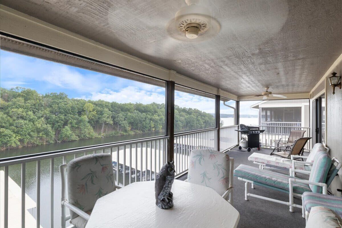 A covered balcony with a table, chairs, and a statue.