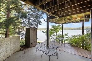 An outdoor deck with a concrete floor, metal benches, and a view of a lake. - The Linn Creek Lodge Family Home With Private Dock (Linn Creek)