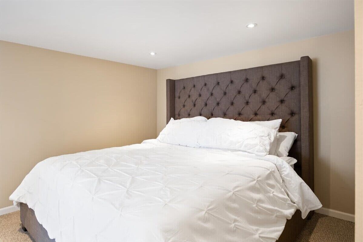 A neatly made bed with a tufted headboard in a hotel room.