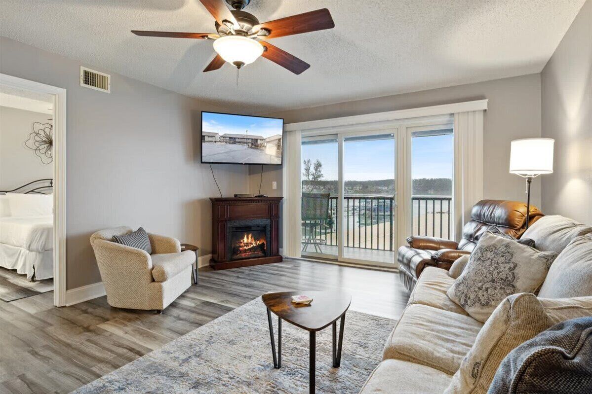 A living room with a fireplace, a ceiling fan, a television, and a sofa.