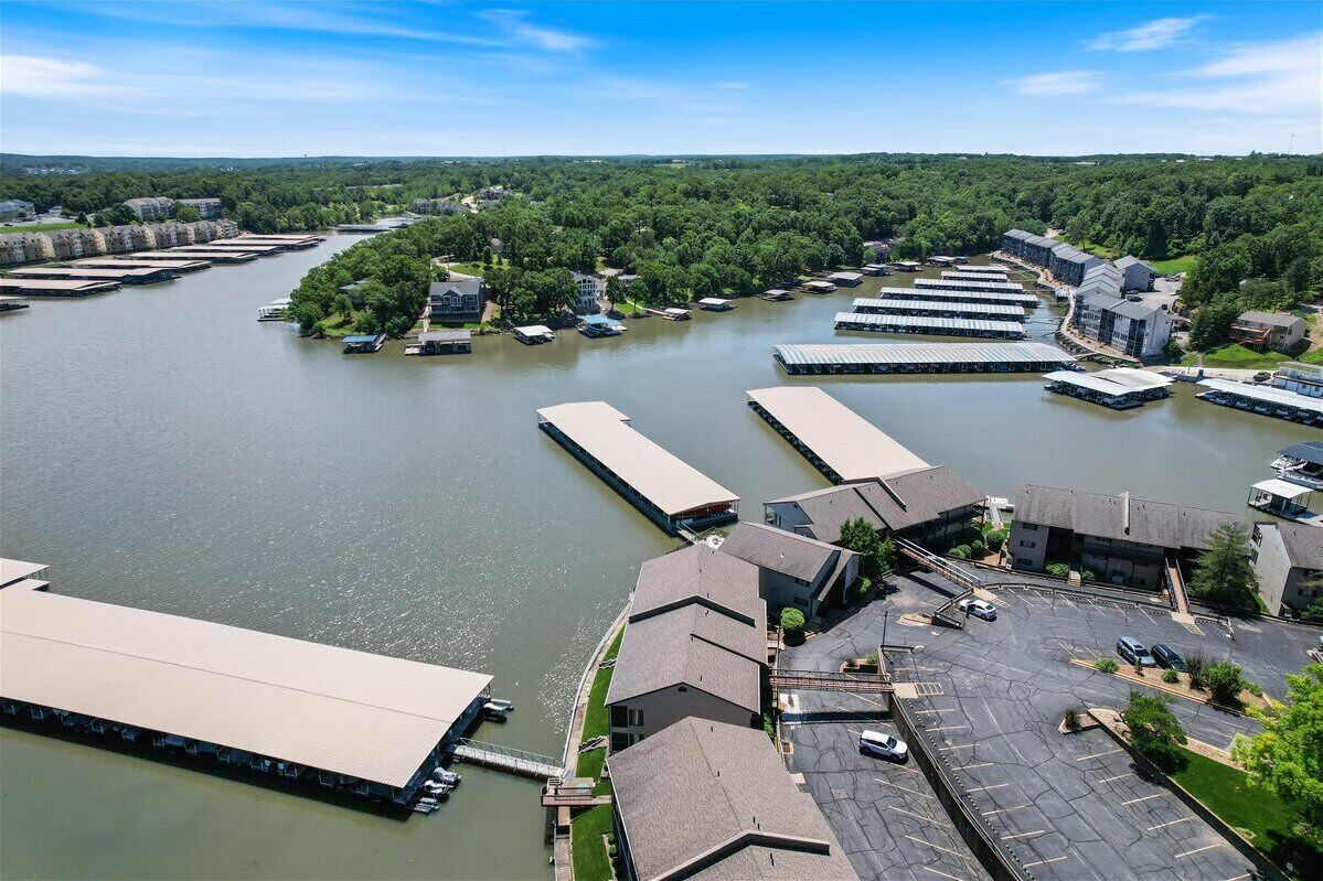 A riverside property with multiple docked boats, a parking area, and buildings with flat roofs.