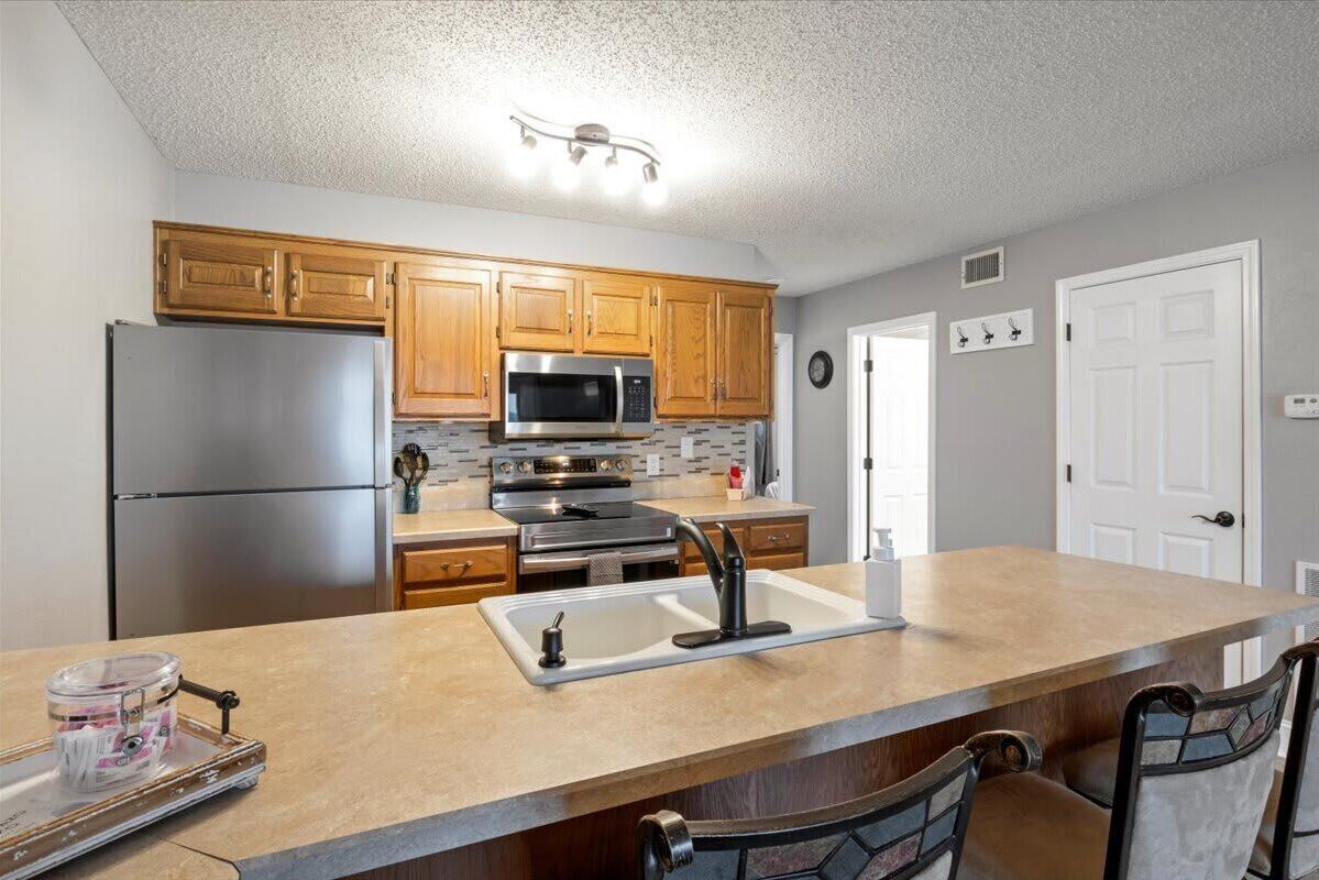 A kitchen with wooden cabinets, stainless steel appliances, a granite countertop, and a sink.