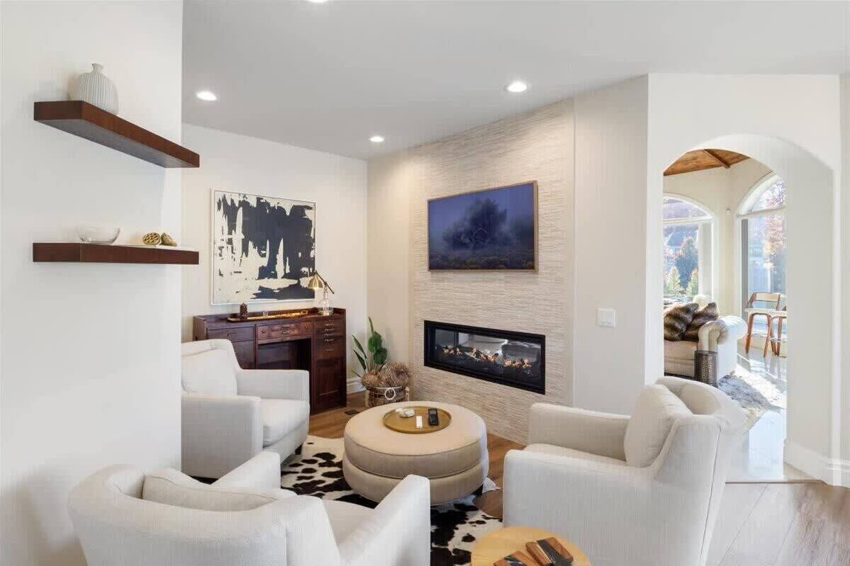 A modern living room with a fireplace, white sofas, and artwork on the walls.
