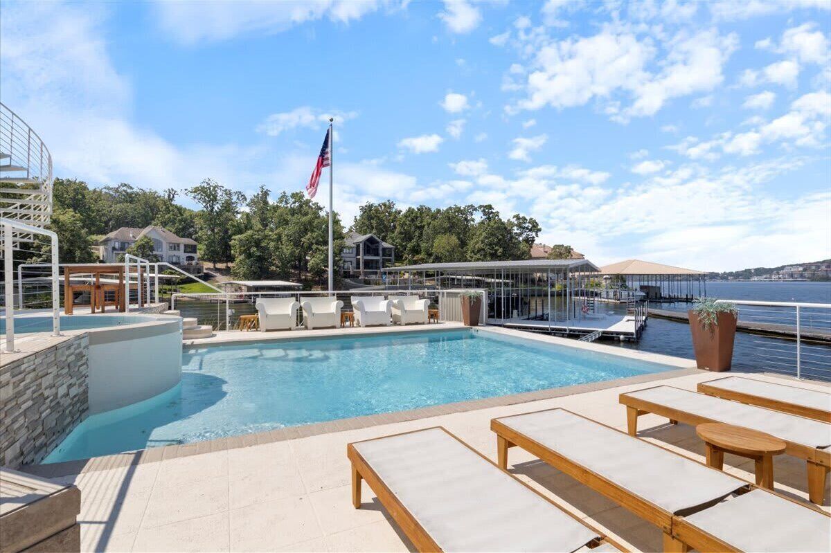 A rooftop pool area with lounge chairs, a flag, and a view of the water.