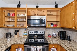 A kitchen with wooden cabinets, a stainless steel microwave, a gas stove, and various kitchen utensils. - Quiet Family 4BR l 3 Full Baths l Near ATL Airport l Sleeps 9 (Union City)