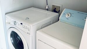 A laundry room with a front-loading washing machine and a stacked dryer.