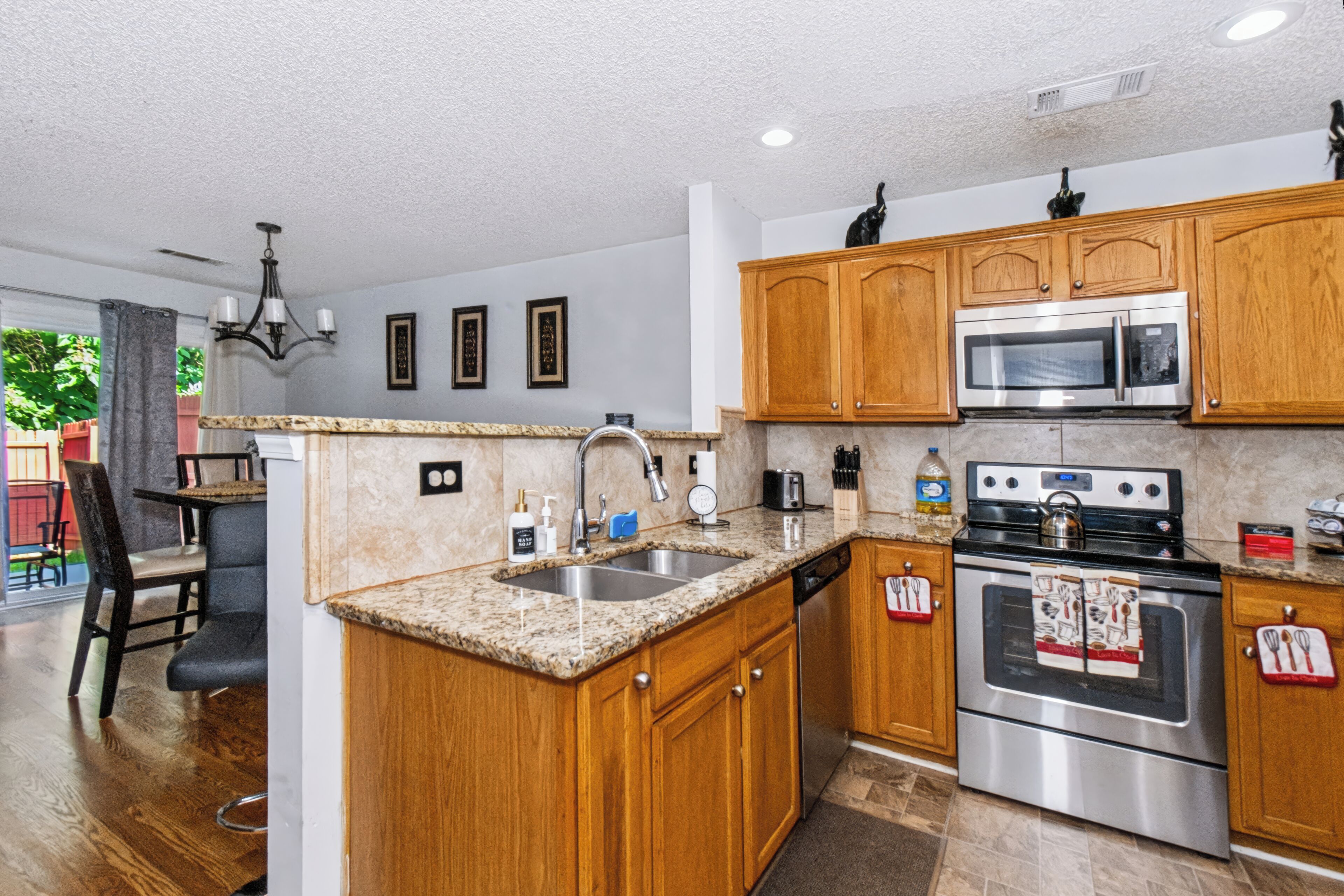 A kitchen with wooden cabinets, stainless steel appliances, a granite countertop, and a view of the outdoors.