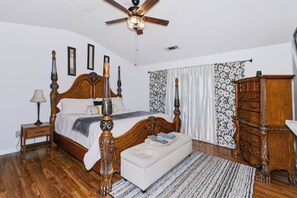 A bedroom with a wooden bed, a nightstand, a dresser, a ceiling fan, and a window with curtains. - Quiet Family 4BR l 3 Full Baths l Near ATL Airport l Sleeps 9 (Union City)