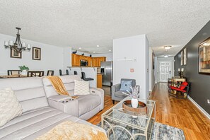 A modern living room with a sofa, coffee table, and a dining area with chairs.