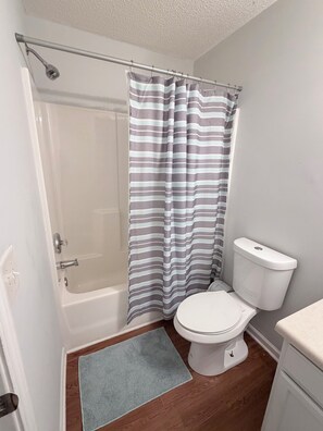 Ein Badezimmer mit Dusche, Toilette und Handtuchhalter.