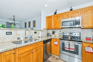 A modern kitchen with wooden cabinets, stainless steel appliances, and a granite countertop.
