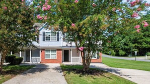 A two-story house with a front porch, a driveway, and a well-maintained lawn.