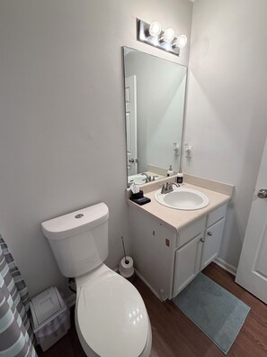 Ein Badezimmer mit Toilette, Waschbecken, Spiegel und einer kleinen Mülleimer.