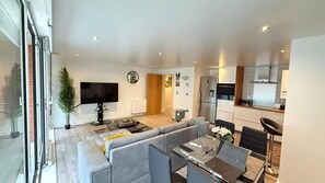 A modern living room with a sofa, TV, and dining area. - Cosy London Apartment Near City Centre (London)