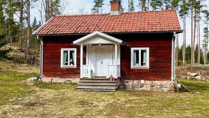 A red wooden house with a tiled roof, a front porch, and a chimney. - 2 Person Holiday Home in Morlunda (Mörlunda)