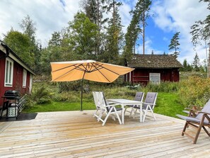 Eine Holzterrasse mit Gartenmöbeln, einem Tisch und einem Sonnenschirm.