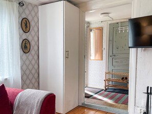 A room with a wardrobe, a bed with a patterned bedspread, a wall with decorative frames, a door with a mirror, and a shoe rack. - 2 Person Holiday Home in Morlunda (Mörlunda)