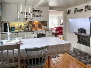 Una cocina compacta con zona de comedor, piso de madera y un sofá rojo al fondo.