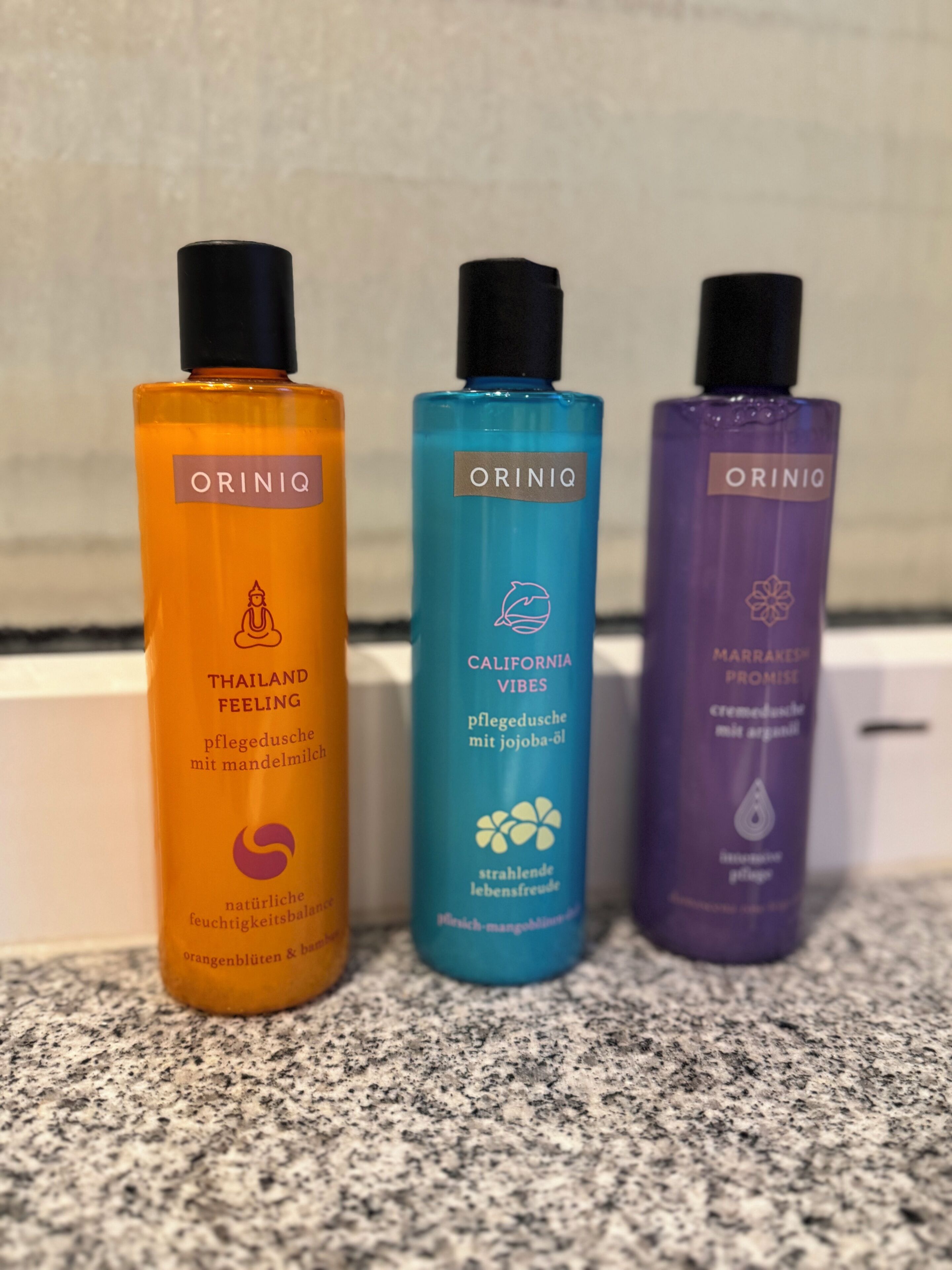 Drie flessen Oriniq huidverzorgingsproducten op een aanrecht.