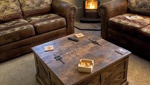 Un salon avec deux canapés en cuir, une table basse en bois et un poêle à bois.