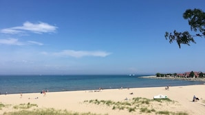 Ein Strand mit Menschen, wolkenlosem Himmel und ruhiger See.