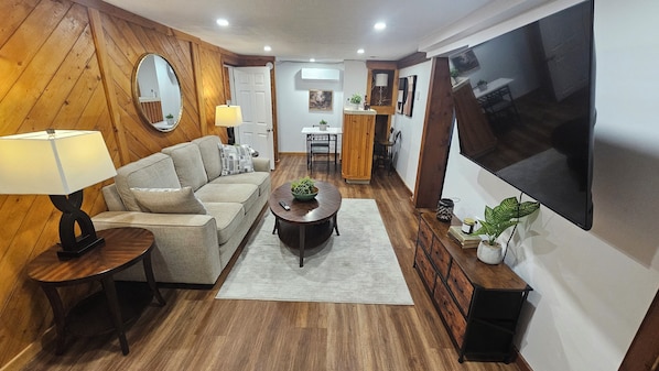 A living room with a sofa, coffee table, TV, and wooden walls.