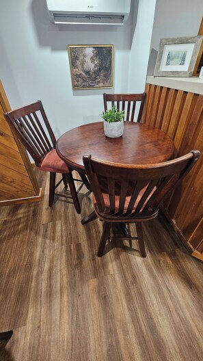 A round wooden dining table with four chairs, a potted plant, and a painting on the wall. - Modern Basement Apartment / Private and Comfortable (Saint John)
