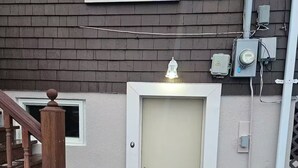 En bostadsbyggnad med en trätrappa, en beige dörr och ett fönster.