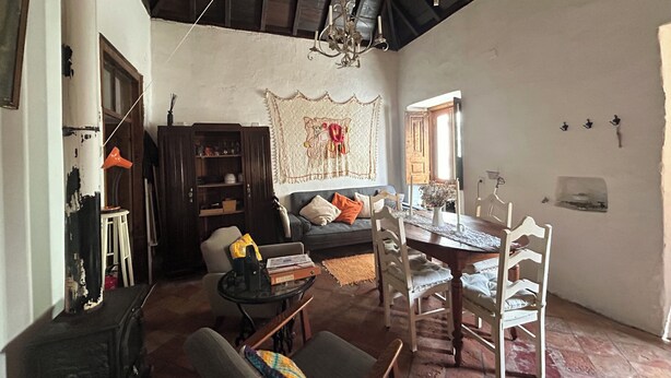 Una habitación con una mesa de comedor, sillas, un sofá, una estantería y una araña.
