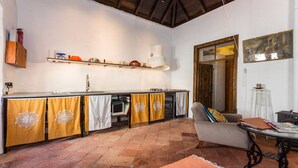 Una cocina con piso de baldosas, una zona de comedor con mesa y sillas, y un acceso a otra habitación.