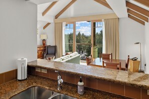 A kitchen with granite countertops, a sink, and a view of a balcony with a sofa and chairs. - Luxury 2BR Penthouse with Lodge Pool Access in Suncadia Resort (Cle Elum)