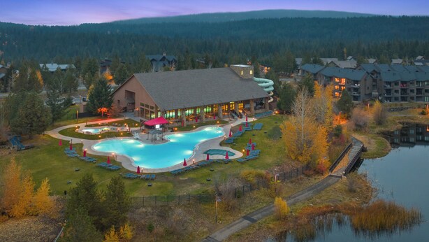 Un complexe hôtelier doté d’une grande piscine, d’un espace abrité et offrant une vue sur une chaîne de montagnes boisées.