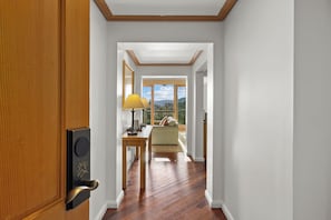A hallway with a wooden door, a table with a lamp, a sofa, and a window with a view of the outdoors. - Luxury 2BR Penthouse with Lodge Pool Access in Suncadia Resort (Cle Elum)