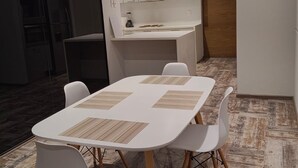 A modern dining area with a white table and chairs, a kitchen in the background, and a wooden floor. - Modern apartment with pool and gym in TOP location in the CDMX (Ciudad de México)