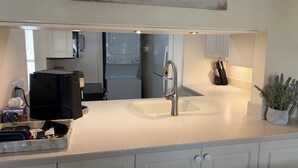 A kitchen with a countertop, a sink, cabinets, a coffee maker, and a potted plant. - Great beach access, central location, 2-bedroom condo in wonderful Marco Island (Marco Island)