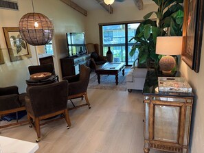 A living room with a television, leather chairs, a coffee table, and a large plant. - Great beach access, central location, 2-bedroom condo in wonderful Marco Island (Marco Island)