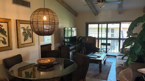 A living room with a glass table, chairs, a sofa, a television, and a ceiling fan. - Great beach access, central location, 2-bedroom condo in wonderful Marco Island (Marco Island)