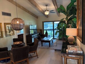 A living room with a television, seating, a large plant, and a ceiling fan. - Great beach access, central location, 2-bedroom condo in wonderful Marco Island (Marco Island)