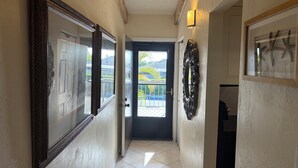 A hallway with a door leading to a balcony, a large mirror, and a wall-mounted light fixture. - Great beach access, central location, 2-bedroom condo in wonderful Marco Island (Marco Island)